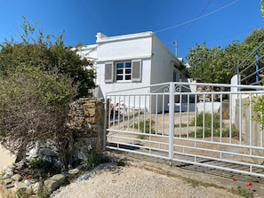 A white building with a stone wall, a metal gate, and a clear blue sky.