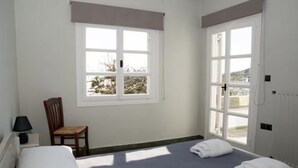 Une pièce avec un lit, une chaise, une fenêtre et un radiateur.