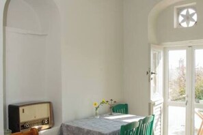 A room with a table, chairs, a radio, and a window with a view.