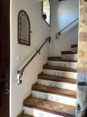 Eine Treppe mit gemusterten Fliesen, einem Metallgeländer und einem dekorativen Spiegel.