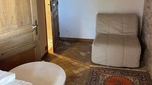 Een kamer met een houten deur, een beige bank, een kamerbreed tapijt en een betegelde vloer.