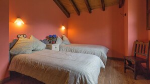 Un dormitorio con dos camas, una mesita de noche, una silla y techo de madera.