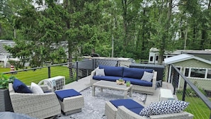 A covered outdoor patio with wicker furniture, a table, and a grill.