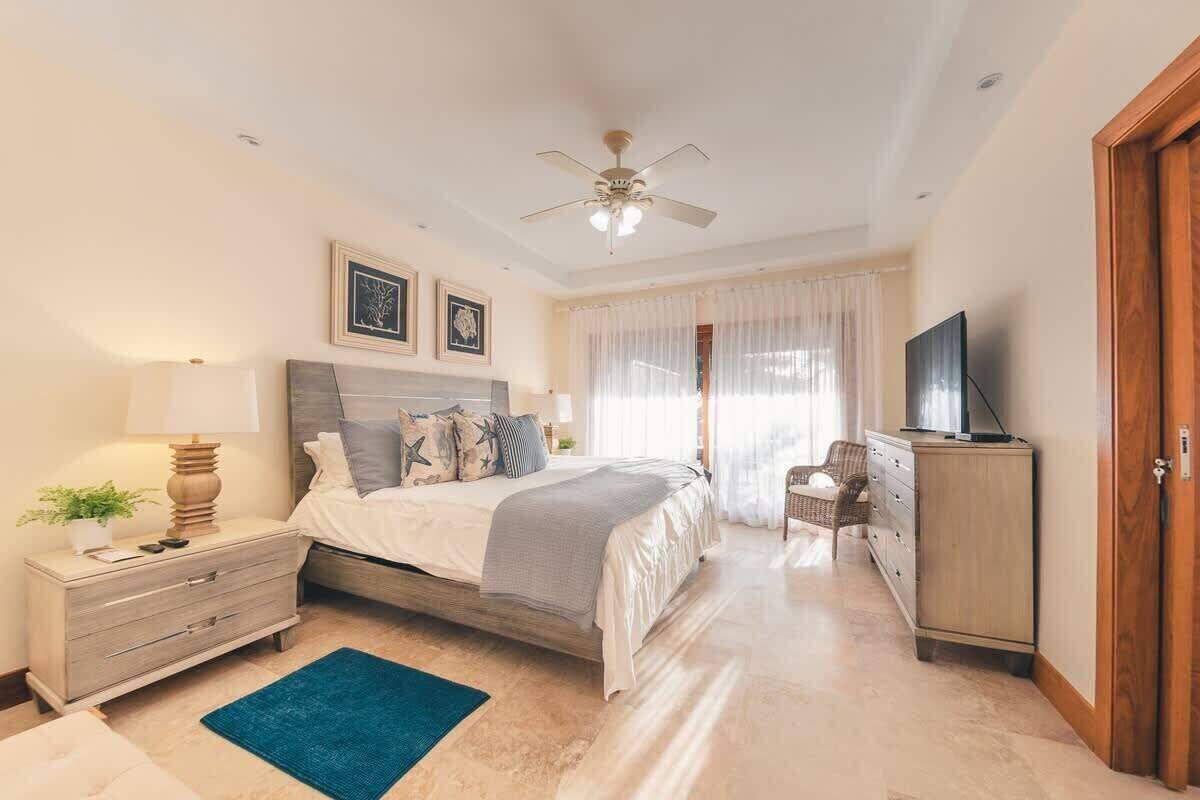 A bedroom with a bed, nightstand, dresser, television, and a ceiling fan.