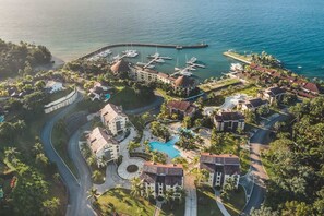 Vue aérienne d’un complexe hôtelier doté d’un port de plaisance, d’une piscine et d’une végétation luxuriante.