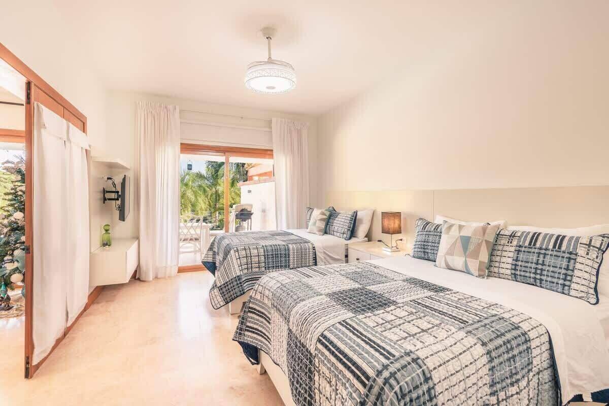 A hotel room with two beds, a large window, and a view of the outdoors.