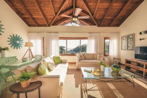 A spacious living room with a high ceiling, wooden beams, a glass coffee table, and a television on a wooden stand. - AEA- Samana Dominican Republic (Sanchez)