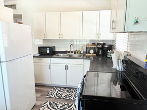 A kitchen with white cabinets, a microwave, a coffee maker, and a sink. - 10 Min to Gulf Coast Beaches - Pet Friendly - Fenced Yard (Seminole)