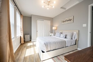 Ein Schlafzimmer mit Bett, Nachttisch, Lampe, Heizkörper und Tür.