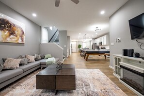 Ein modernes Wohnzimmer mit Sofa, Couchtisch und Essbereich inklusive Billardtisch.