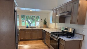 Une cuisine moderne avec des meubles en bois, une cuisinière en acier inoxydable et un plan de travail en marbre.