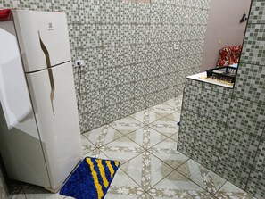 Una cuina petita amb nevera, salabroc d'azulejos i un terrapatró.
