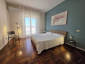 Ein Schlafzimmer mit einem Bett, einem Sessel, einer Stehlampe und einem Bild an der Wand.
