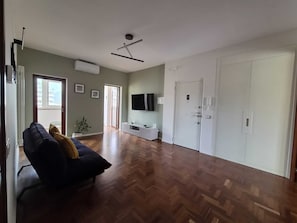 Ein geräumiger Wohnbereich mit einer Couch, einem Fernseher und einer weißen Tür.
