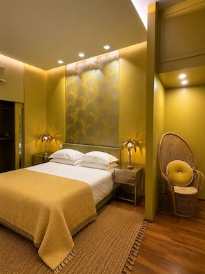 A bedroom with a bed, two bedside tables with lamps, a chair, and a patterned wall. - Luxury beachfront apartment (Napoli)