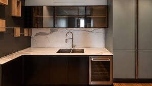 Een moderne keuken met een marmeren aanrechtblad, inbouwmeubels, een roestvrijstalen spoelbak en een inbouwoven.