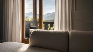 Une chambre avec un lit, une fenêtre avec des rideaux et une vue sur les montagnes.