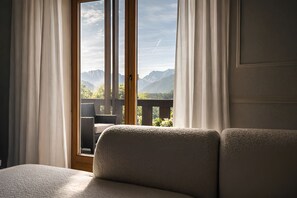 Ein Zimmer mit Bett, einem fensterbelaubten Fenster und Bergblick.