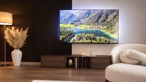 Un salon moderne avec un téléviseur à écran plat, un canapé blanc, une lampe et un vase décoratif.