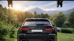 Une voiture noire est garée sur un chemin, avec des montagnes en arrière-plan.