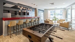 A modern bar area with a foosball table, bar stools, and a seating area with chairs and a sofa. - Apartment located in downtown Los Angeles across from the convention center (Los Angeles)