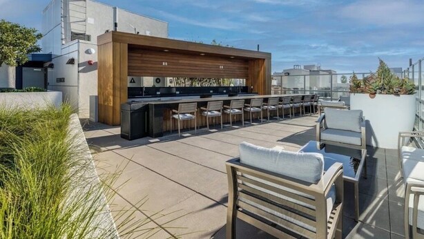 A rooftop bar with a long counter, multiple chairs, and a wooden panel backdrop. - Apartment located in downtown Los Angeles across from the convention center (Los Angeles)