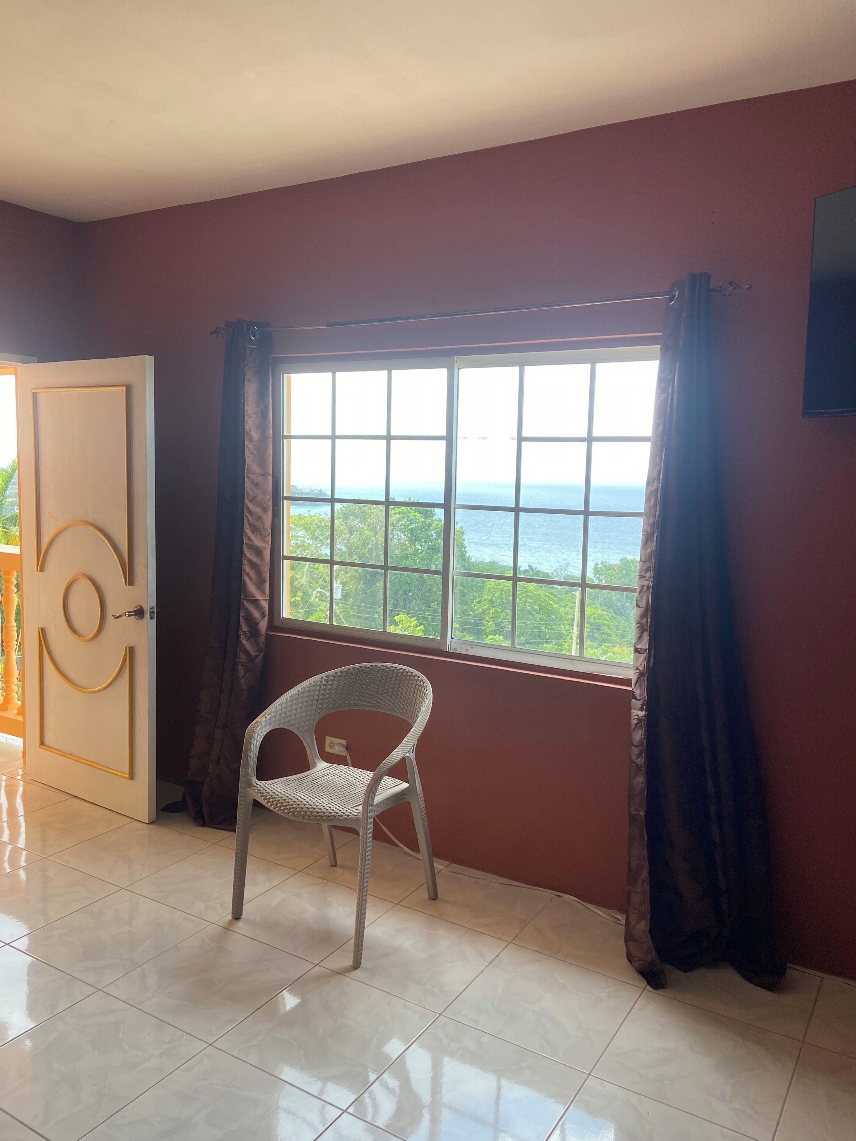 A room with a large window, a chair, and a door.
