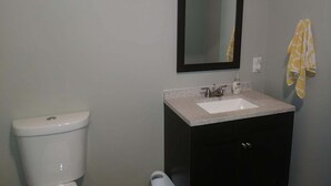 Ein Badezimmer mit Toilette, Waschbecken, Spiegel und Handtuchhalter.