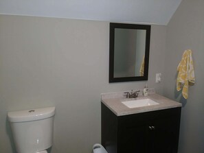 Ein Badezimmer mit Toilette, Waschbecken, Spiegel und Handtuchhalter.
