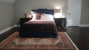 Ein Schlafzimmer mit Bett, Nachttischen, Teppich und einer Tür.