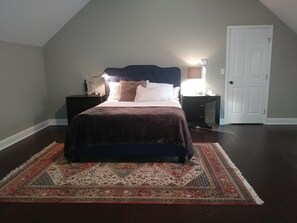 Ein Schlafzimmer mit Bett, Nachttischen, Teppich und einer Tür.