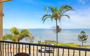 A balcony with a view of the sea, a palm tree, and a parked truck. - Four, Villa Mar Colina (Yeppoon)