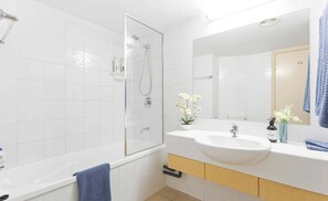 A modern bathroom with a glass shower enclosure, a white sink, and a mirror. - Four, Villa Mar Colina (Yeppoon)