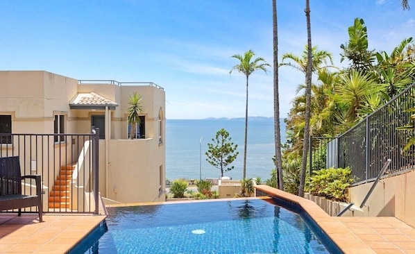 A swimming pool with a view of the sea, a staircase, and palm trees. - Four, Villa Mar Colina (Yeppoon)