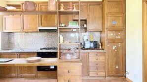 A kitchen with wooden cabinets, a granite countertop, a microwave, and a dish rack. - C015 – Camerano – Three-story villa with garden (Camerano)