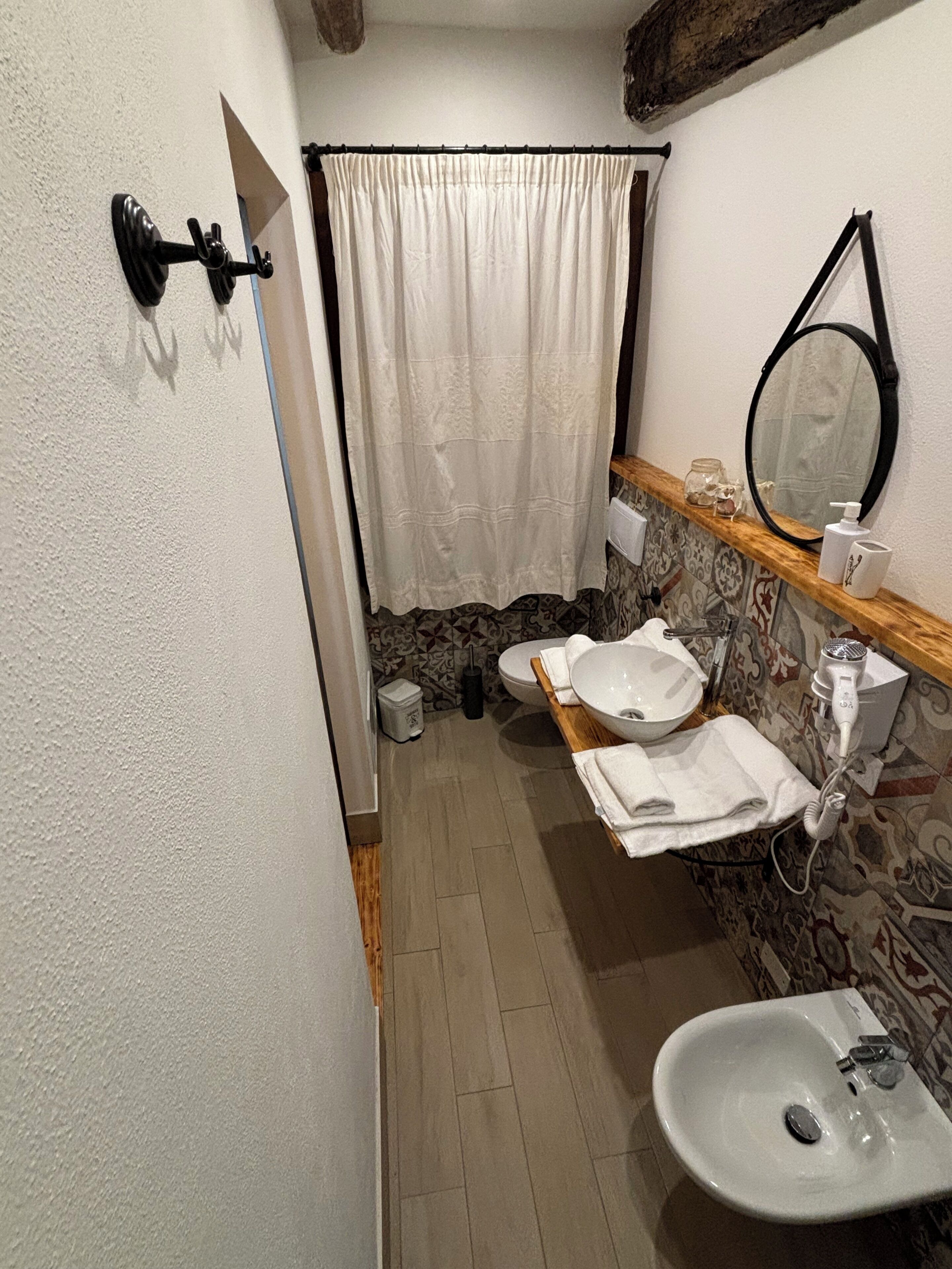 Ein Badezimmer mit einem weißen Waschbecken, einem Spiegel, einem Handtuchhalter, einer Toilette und einer Duschvorhang.