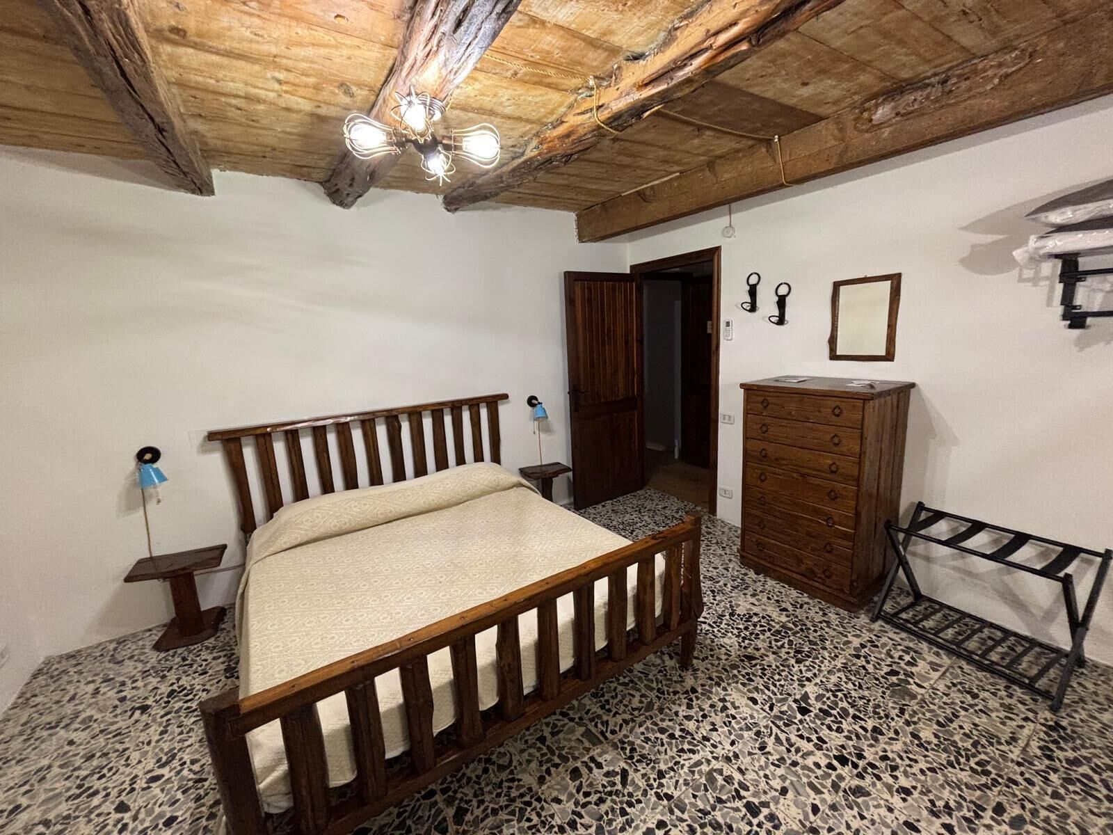 A bedroom with a wooden bed, a dresser, a mirror, and a ceiling fan.