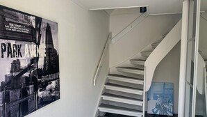 Una escalera con barandillas blancas y un cartel blanco y negro de un paisaje urbano en la pared.