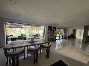 A spacious dining area with a large table and chairs, a view of a swimming pool, and a patio with outdoor furniture.