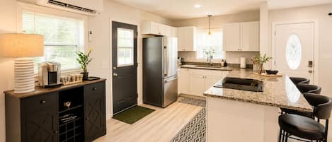 A modern kitchen with a central island, built-in appliances, and a dining area with bar stools.