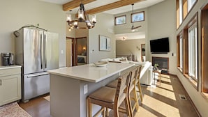 A spacious kitchen with a large island, wooden beams, and a modern chandelier.