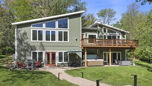 A two-story house with a deck, outdoor seating, and a hot tub.