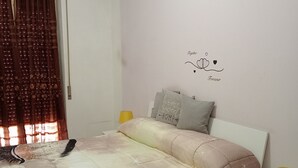 Ein Schlafzimmer mit Bett, Nachttisch, Lampe, Wandklimaanlage und Wanddeko.