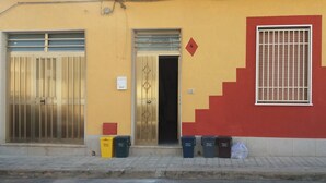 Ein Gebäude mit gelber Fassade, einem Metallgitter und einer roten Treppe.