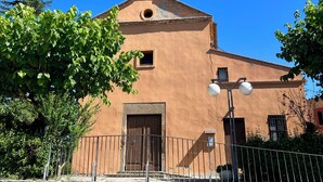A building with a bell tower, a wooden door, and a stone wall in front.