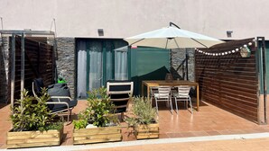A patio with a table and chairs, potted plants, and a covered area.