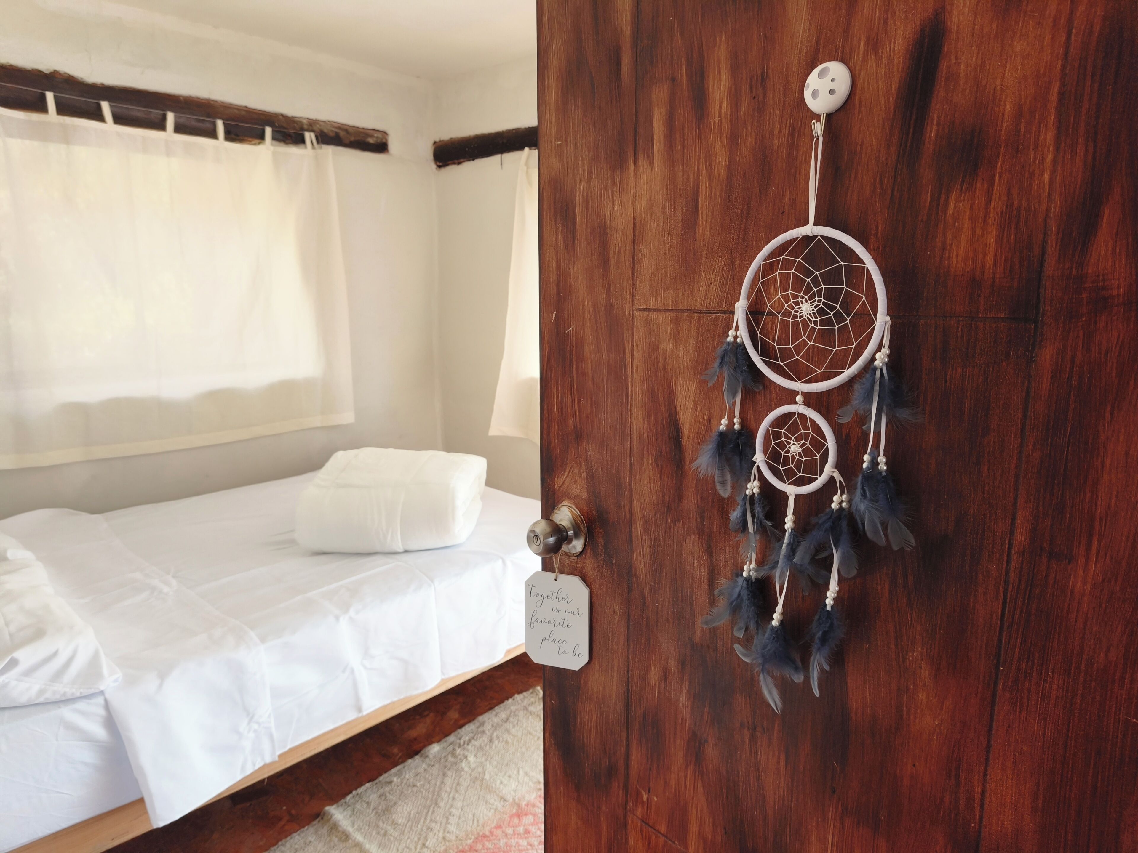 Ein Schlafzimmer mit einem Bett, einer Holztür und einem Türschild mit einem Traumfänger.
