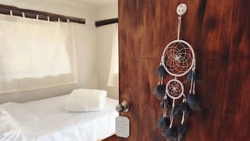 Ein Schlafzimmer mit einem Bett, einer Holztür und einem Türschild mit einem Traumfänger.