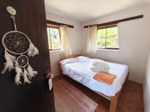 Une chambre à coucher avec un lit, un attrape-rêves, une fenêtre et une porte.