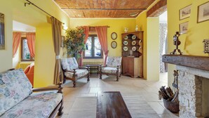 Ein Wohnzimmer mit Ziegeldecke, gelben Wänden, floralen Sofas, einem Holztisch und einem Kamin.